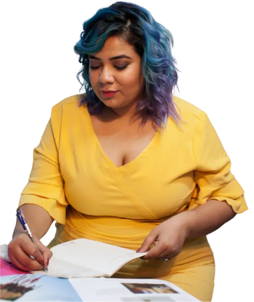 Mujer con un vestido amarillo con el cabello azul está escribiendo en un cuaderno.