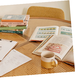 Unos pocos libros y una taza colocados sobre la mesa